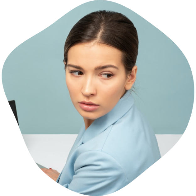 a woman in a blue suit sitting at a desk with a laptop.